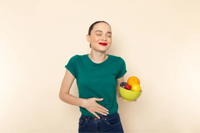 Close up of a woman holding fresh fruits and smiling, symbolising a balanced diet and healthy microbiome support